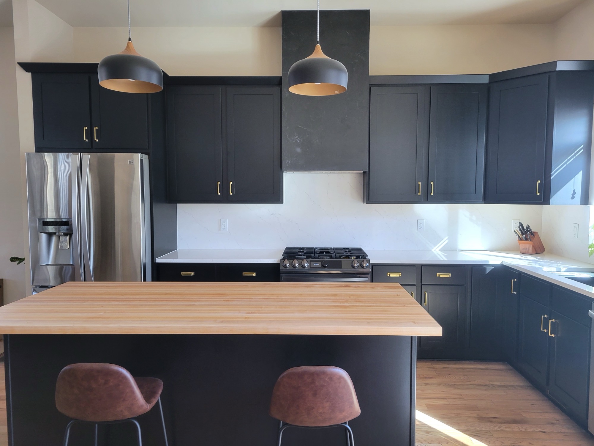 Navy cabinets with butcher block island and copper pendants