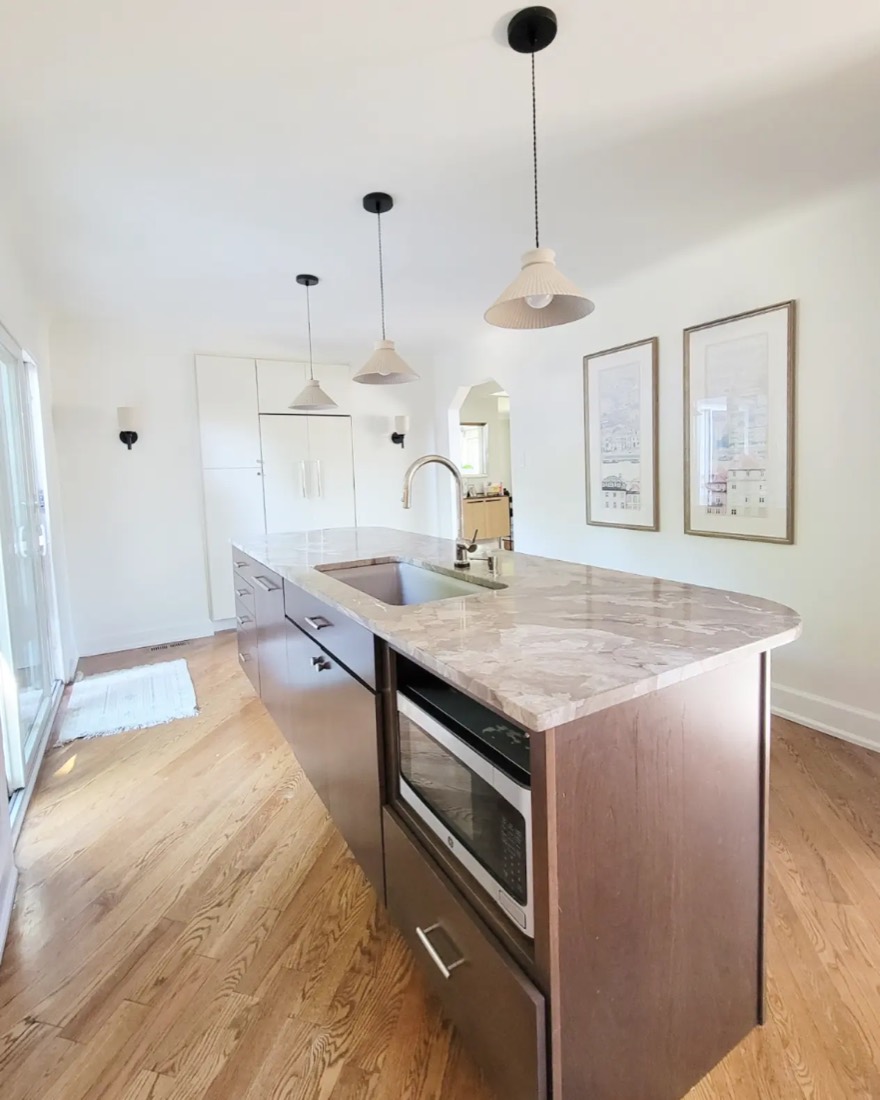 Kitchen island with taupe stone counter and brass faucet
