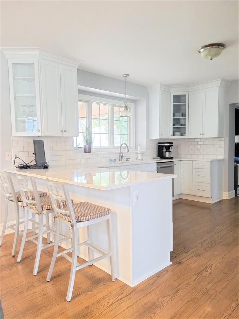 White kitchen peninsula with woven counter stools